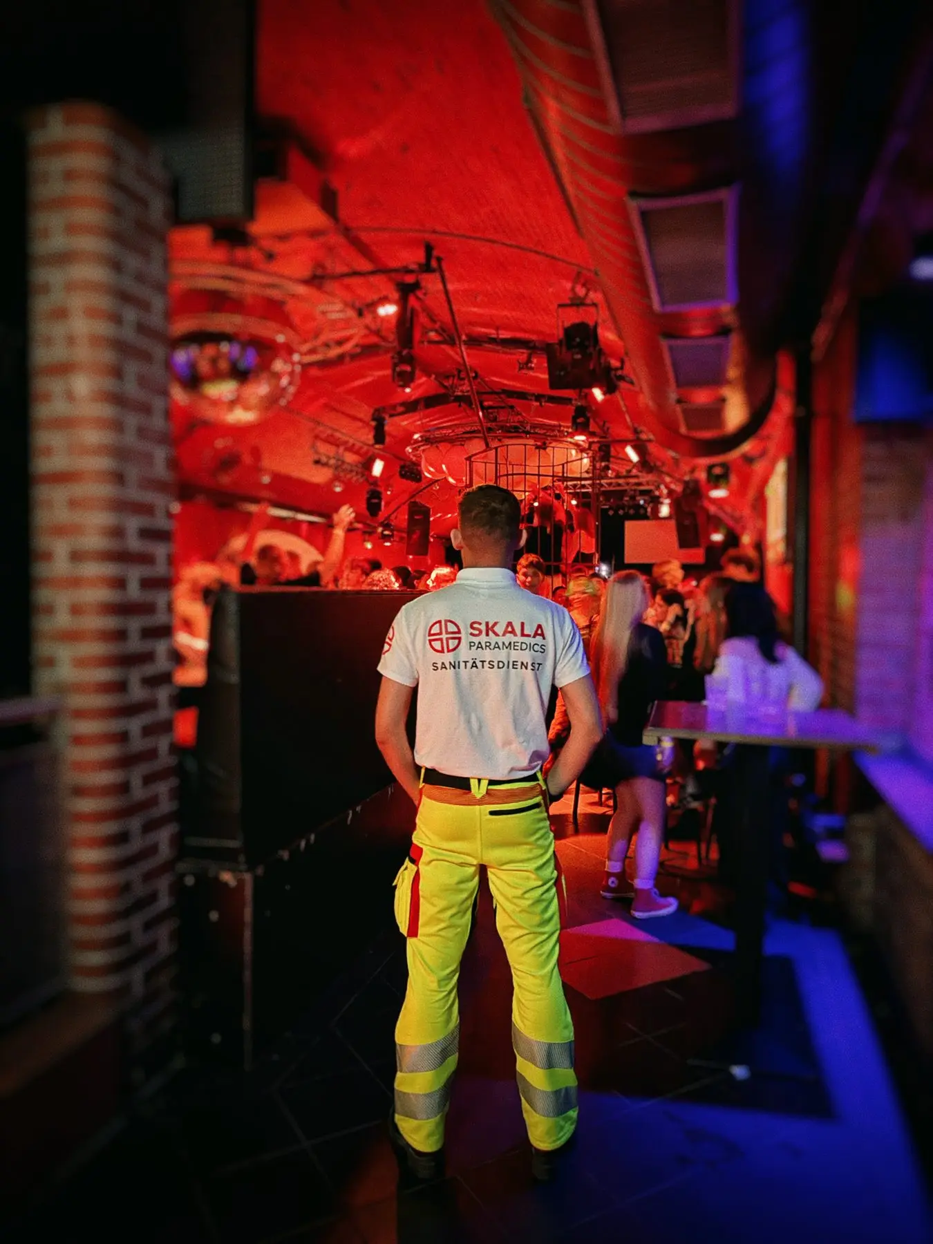 Sanitäter von SKALA Paramedics im rot beleuchteten Club, von hinten