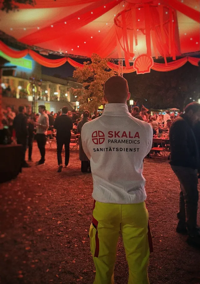 SKALA Paramedics medic in a red-lit festival tent, seen from behind