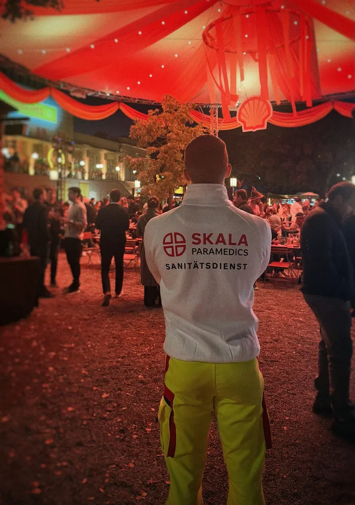 Sanitäter von SKALA Paramedics in einem rot beleuchteten Festzelt, von hinten