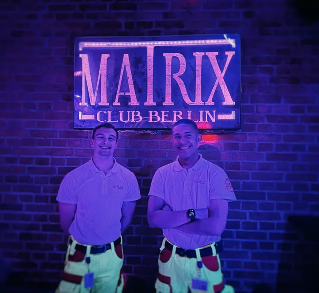 Two SKALA Paramedics medics in front of the neon sign of Matrix Club Berlin