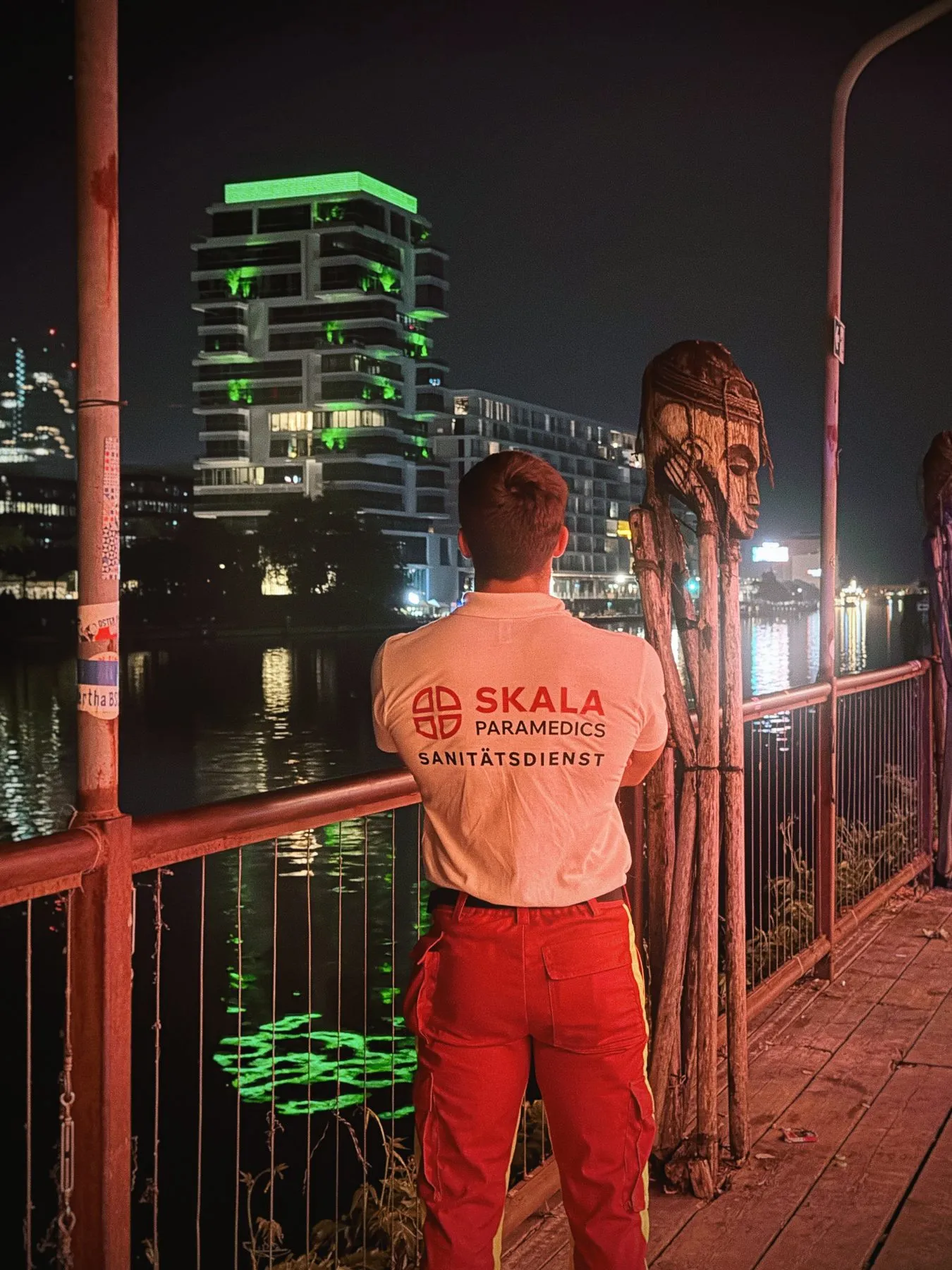 Sanitäter von SKALA Paramedics an einem Geländer mit Blick auf die beleuchtete Stadt