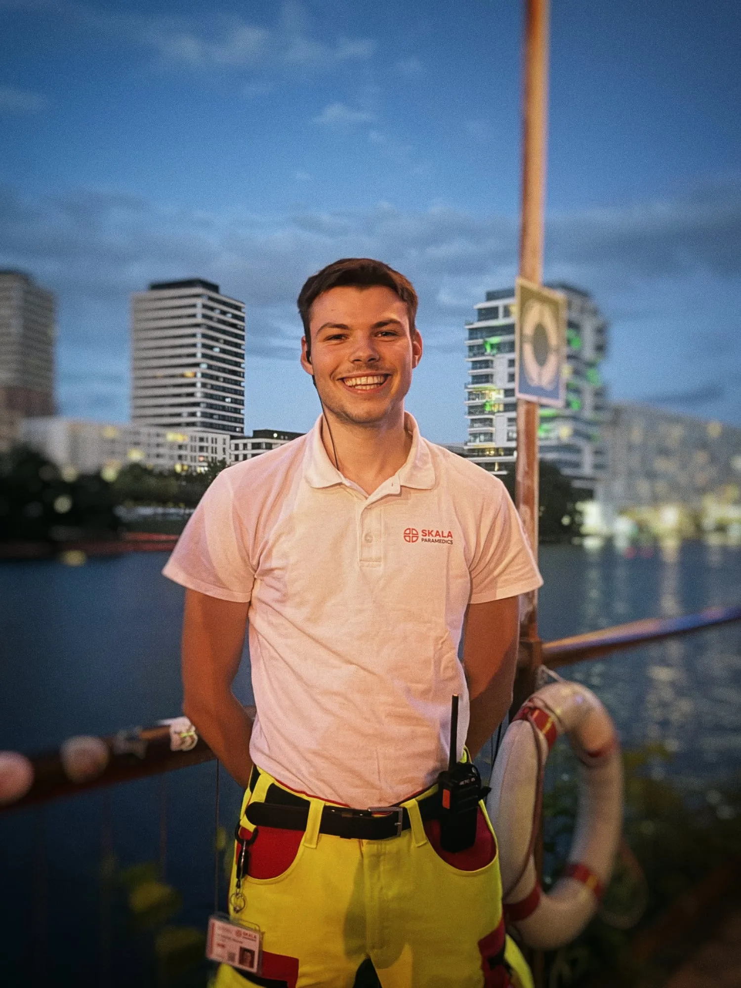 Lächelnder Sanitäter von SKALA Paramedics mit Funkgerät am Abend an der Spree