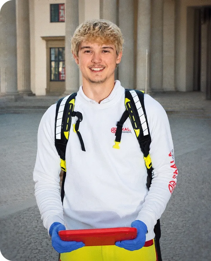 Smiling medic in SKALA uniform with emergency backpack and red tablet