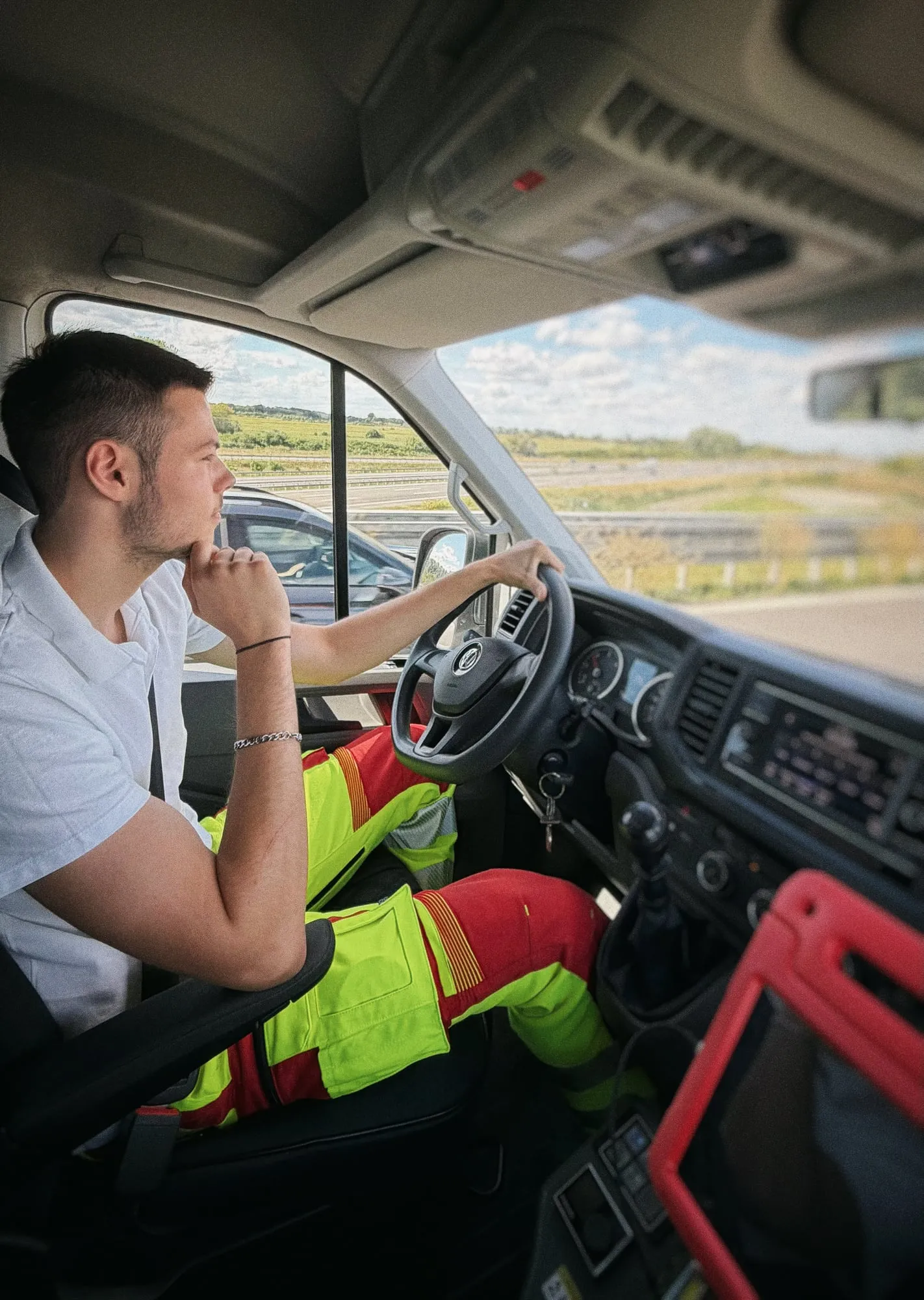 Sanitäter am Steuer des Krankentransportwagens, daneben das rote Einsatz-Tablet
