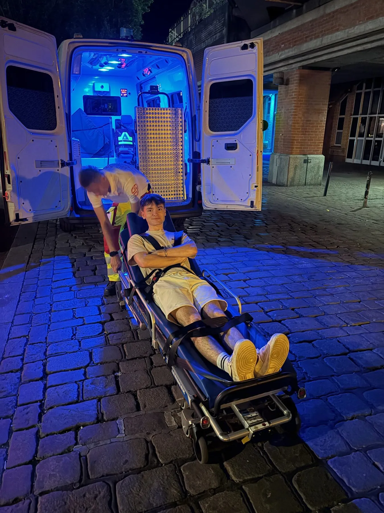 Trage am Heck eines Krankentransportwagens bei Blaulicht in der Nacht