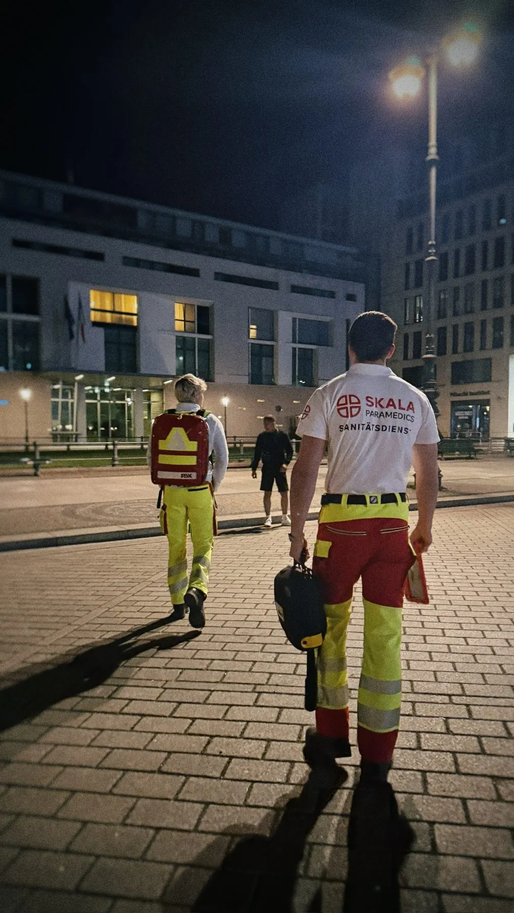 Zwei Sanitäter auf Fußstreife über einen nächtlichen Platz