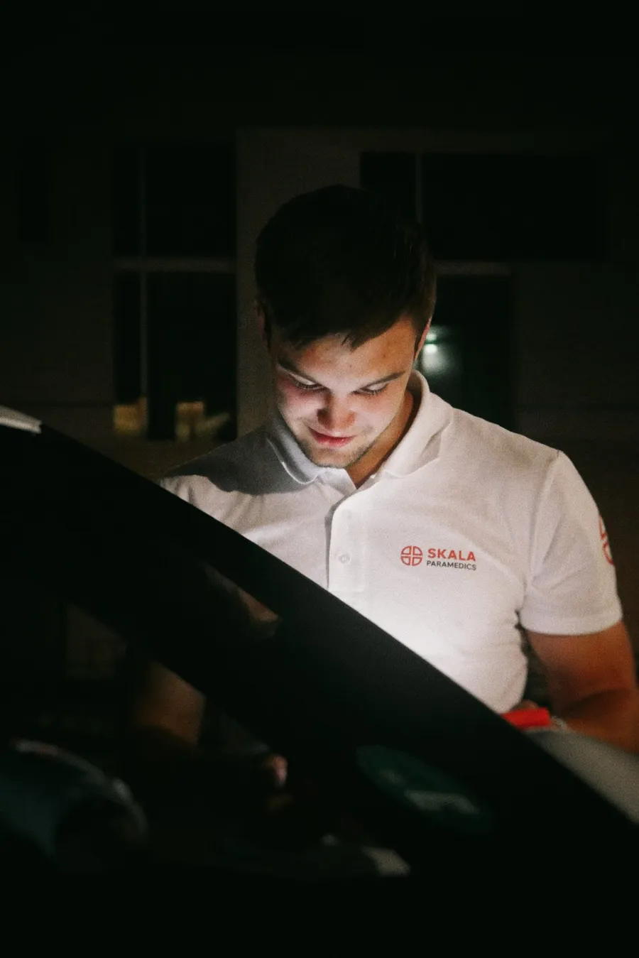 Medic in SKALA uniform checking his deployment tablet at night