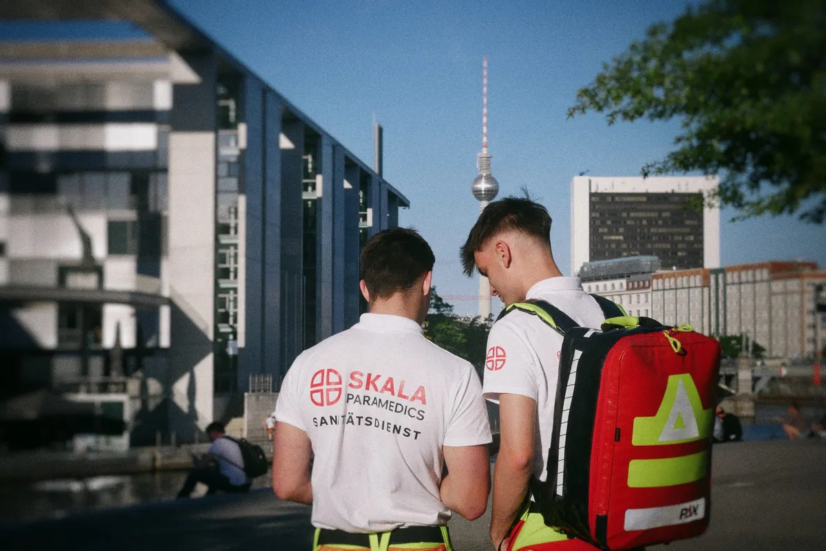 Two medics with an emergency backpack, the Berlin TV Tower in the background